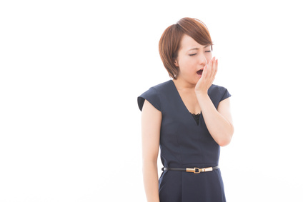 あくびをする疲れ気味の表情の女性