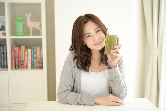 食卓に座りスムージーを片手に笑顔の女性