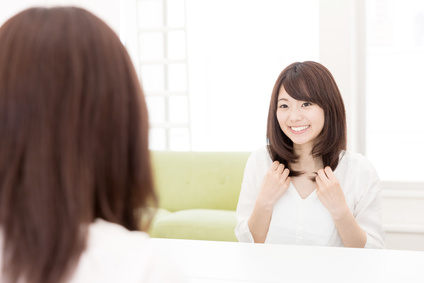 まとまりある髪を鏡でチェックして満足げな女性
