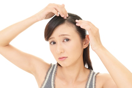 フケが気になって頭皮を指先で確認する女性