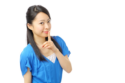 唇を人差し指で抑え笑顔の女性
