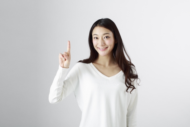 人差し指を立てて1を示す笑顔の女性
