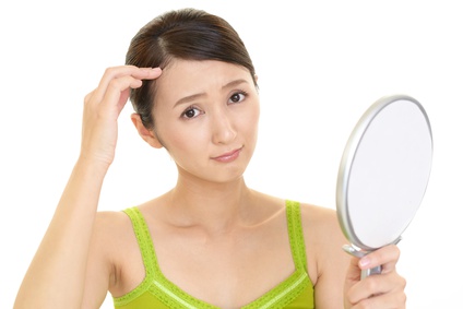 手鏡を持って生え際の薄毛を気にしてる女性