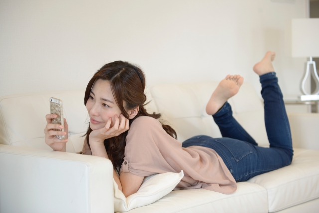 ソファでスマホを見ている女性