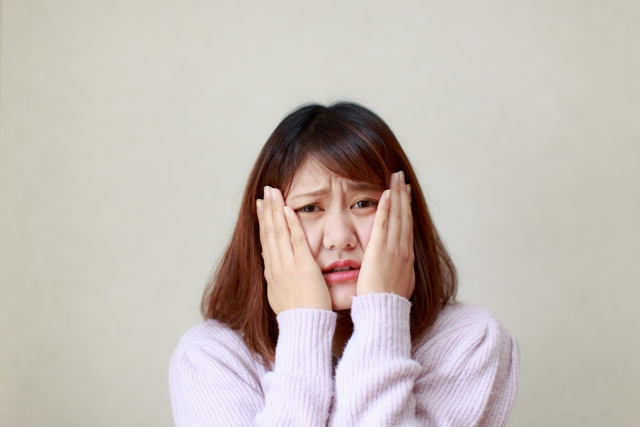 両頬を押さえる女性