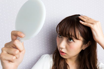 手鏡を持って頭皮をのぞき込む女性