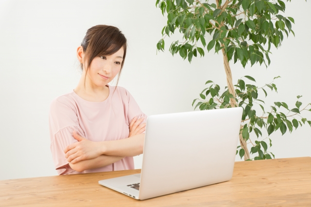 ノートパソコンを見ながら考える女性