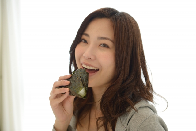 おにぎりを頬張る女性