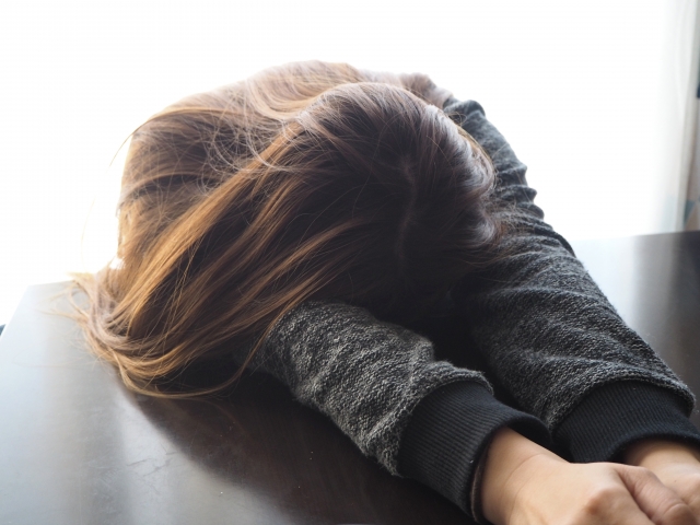 テーブルに顔をうずめる女性