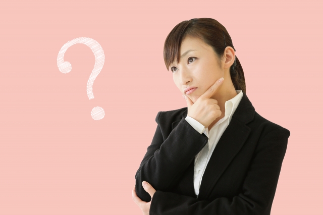 首をかしげるスーツの女性