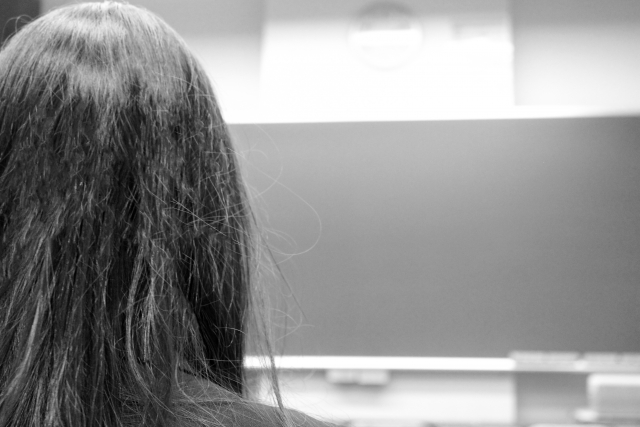 髪が傷んでいる女性の後ろ姿。モノクロ写真