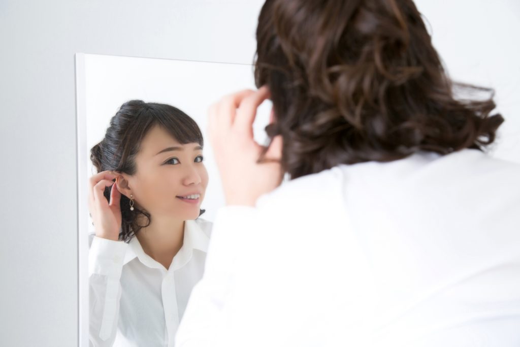 鏡で髪をチェックしている女性