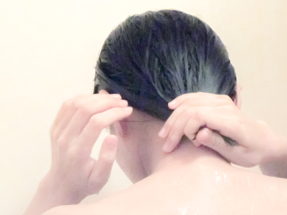 シャワーで頭を洗う女性の後ろ姿